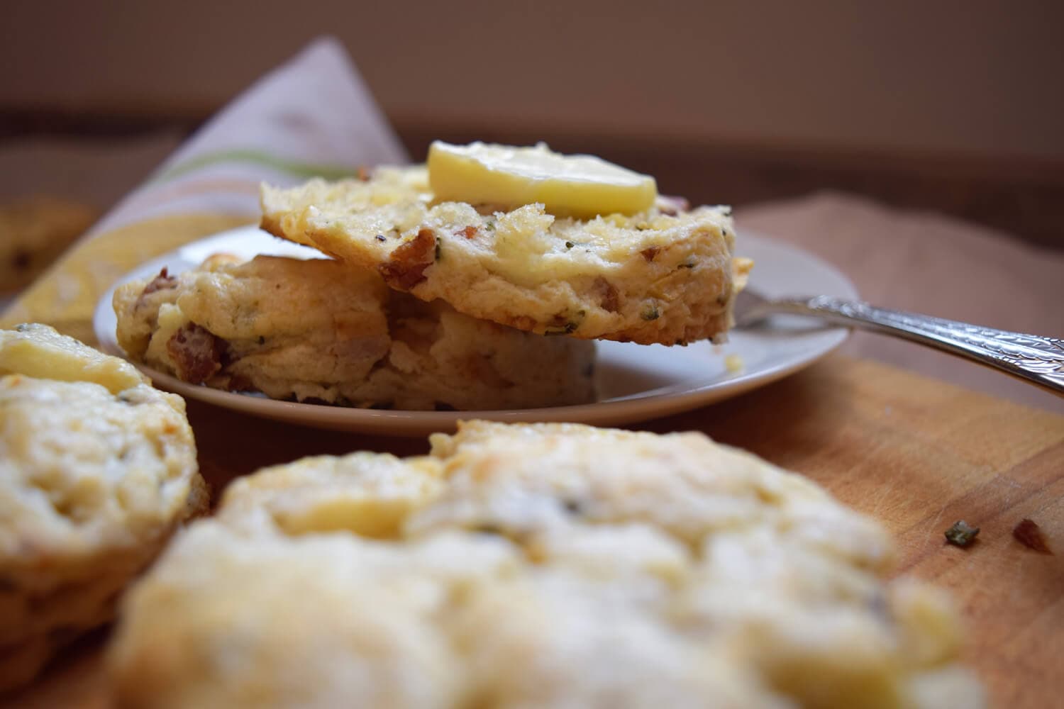 A plate of flaky biscuits topped with a slice of lemon, with more biscuits in the foreground.