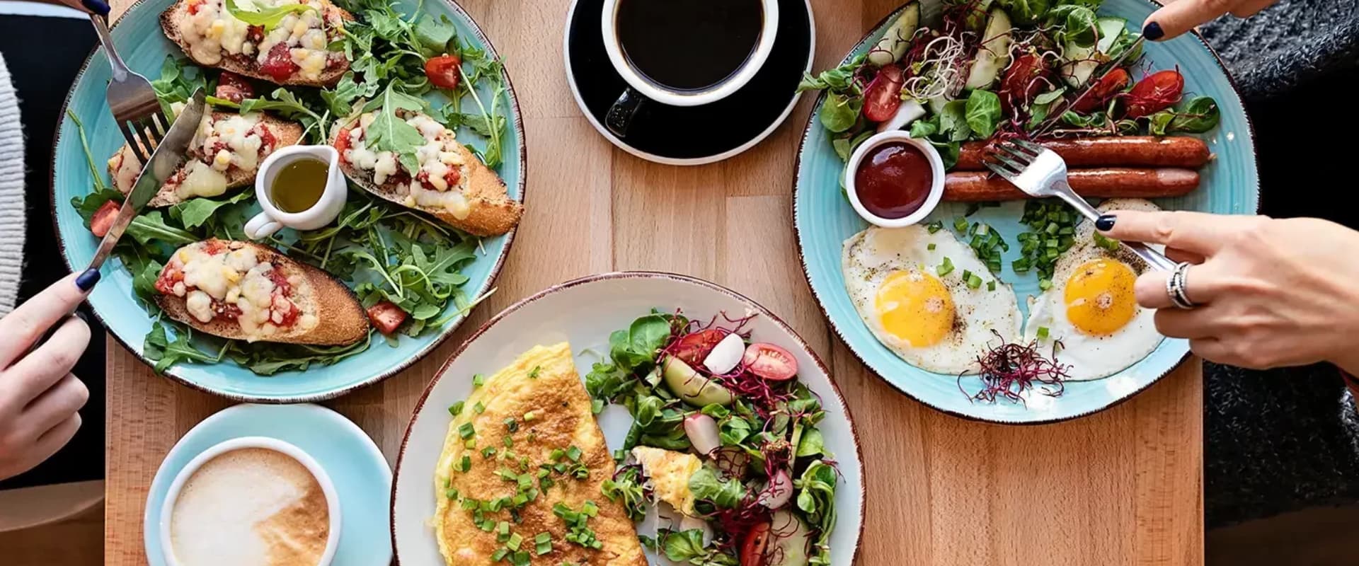 A top view of a brunch spread featuring eggs, sausages, salad, and toast, alongside coffee.
