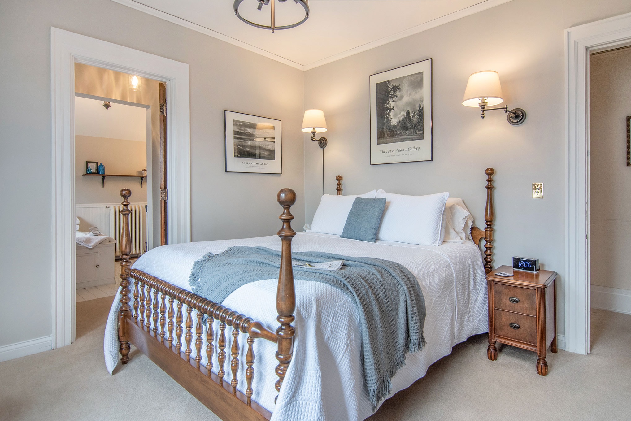 A cozy bedroom featuring a wooden bed, bedside table, and art on the walls.