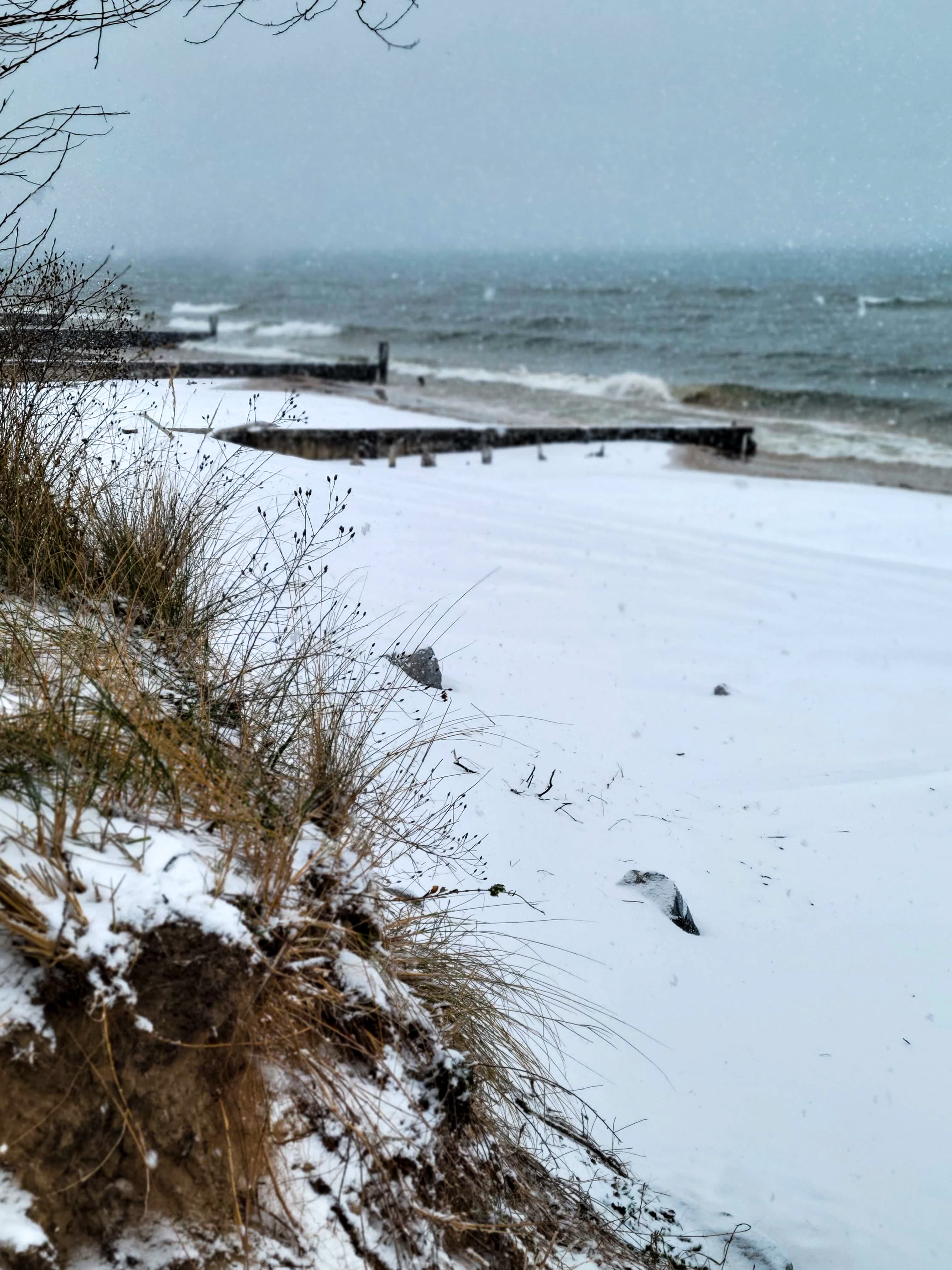 Snow-covered beach with gentle waves and a cloudy sky. Snow-covered beach with gentle waves and a cloudy sky.